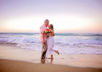 bride kissing groom on beach