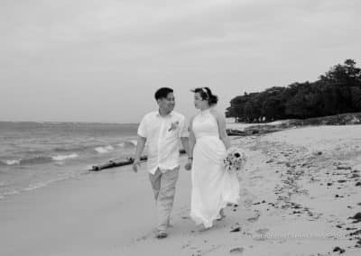bride and groom walk down beach