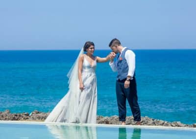 groom kissing brides hand on beach