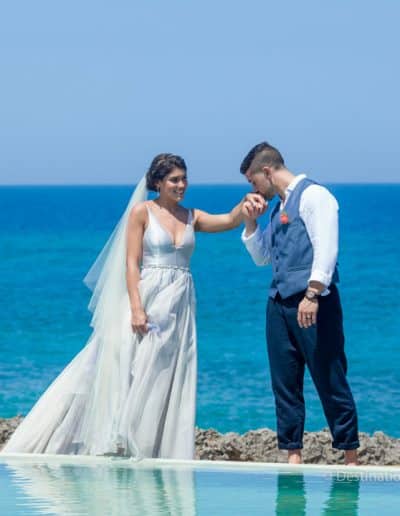 groom kissing brides hand on beach